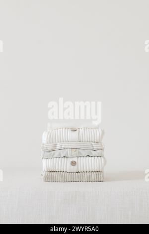 stack of sweaters folded on a linen bench Stock Photo