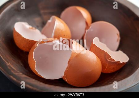 Broken eggshells of chicken brown eggs in wooden kitchen bowl. Organic garbage. Separate waste collection concept. Stock Photo