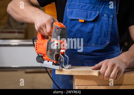 A carpenter using a jigsaw to cut wood cuts bars. Stock Photo