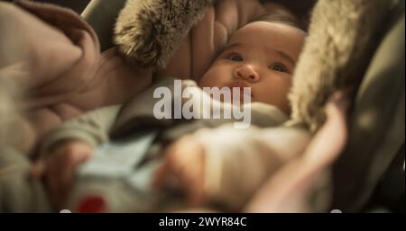 Portrait of a Cute Asian Baby Sitting Calmly in a Car Seat with Safety Belt Securely Attached. Little Adorable Toddler Ready to be Taken Out on Family Trip, Looking Around with Wonder and Innocence Stock Photo