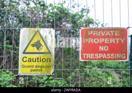 Harefield, UK. 8th April, 2024. Caution Guard Dogs and Private Property No Trespassing signs on the fence of an HS2 construction site in Harefield near where water runs across a country road in Harefield. HS2 have dug up fields, felled numerous trees and destroyed hedges in the area. Waterways across where HS2 are working are having to find new routes which locals believe is exacerbating flooding issues across West London and the Chilterns. Credit: Maureen McLean/Alamy Live News Stock Photo