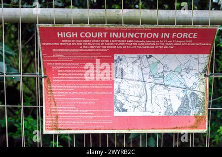 Harefield, UK. 8th April, 2024. An HS2 High Court Injunction sign on the fence of an HS2 construction site in Harefield near where water runs across a country road in Harefield. HS2 have dug up fields, felled numerous trees and destroyed hedges in the area. Waterways across where HS2 are working are having to find new routes which locals believe is exacerbating flooding issues across West London and the Chilterns. Credit: Maureen McLean/Alamy Live News Stock Photo