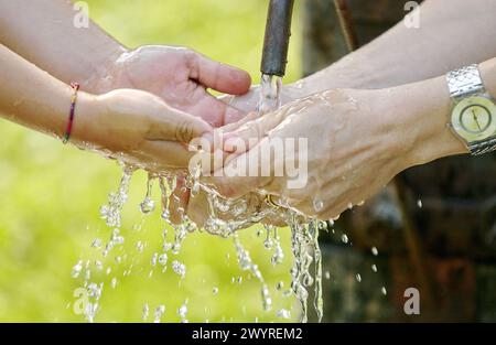 Adult washing kid´s hands in public fountain. Stock Photo