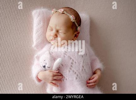 Newborn Girl In Pink Suit Sleeps With Toy Cat During Professional Newborn Photoshoot Stock Photo