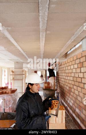 Bricklayer, bricking up a partition wall, new homes under construction, construction site. Stock Photo
