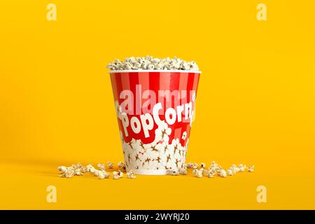 Big bucket of popcorn with spilled corns on yellow background. 3D rendering. Stock Photo