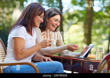 Looking a tablet. Women sisters 35 and 40 years taking coffee on a terrace. Donostia. San Sebastian. Gipuzkoa. Basque Country- Spain. Stock Photo
