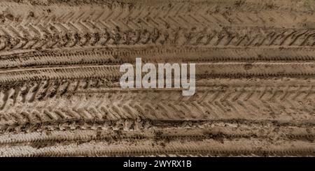 view from above on texture of wet muddy road with puddle and tractor tire tracks in countryside Stock Photo