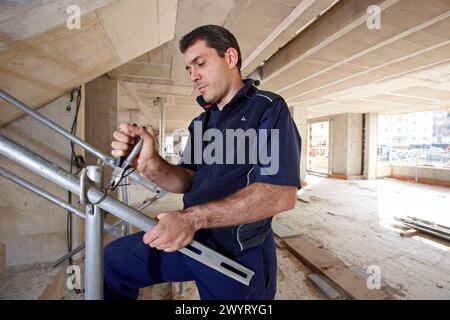 Worker using pliers, new homes under construction, construction site. Stock Photo