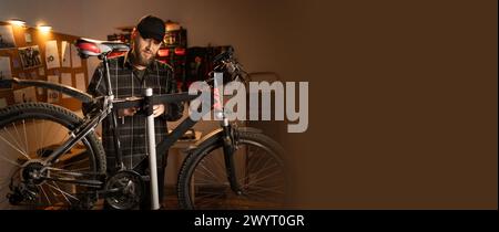 Handsome man in cap, handyman standing with a bicycle in the garage at home. Bicycle repairing and diy concept. Banner. Stock Photo