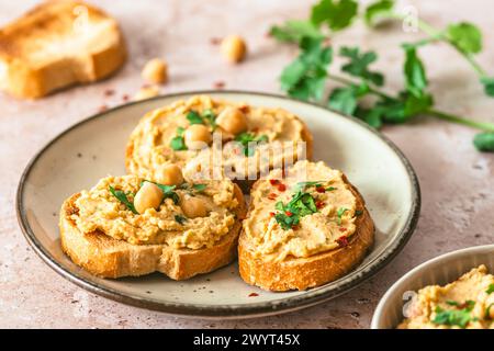 Toasted bread slices with hummus, chickpea puree, on light background Stock Photo