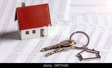 Model house with keys on a French real estate loan schedule document. Concepts of mortgage payments, credit duration and interest rates Stock Photo