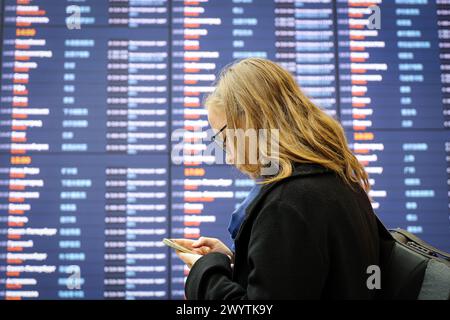 Blonde girl standing near the departure board in Sheremetyevo airport terminal B in Moscow Stock Photo