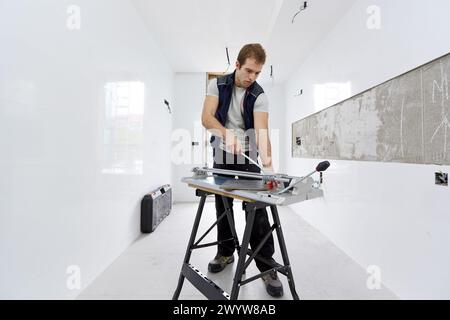 Bricklayer cutting tile. Manual tile cutter. Construction Industry. Stock Photo