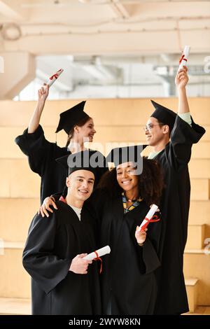 Diverse group of students in graduation gowns and caps posing happily for a picture. Stock Photo