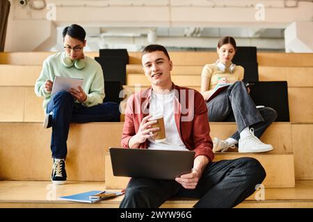A man, of African American descent, sits on stairs while holding a laptop, engaged in educational activities. Stock Photo