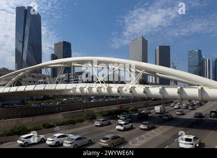 Cars and a train passing under Yehudit Bridge, a bicycle and pedestrian bridge built over the Ayalon Highway, in Tel Aviv Israel Stock Photo