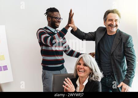 Diverse group of multicultural colleagues shares a high five the office, celebrating a collective achievement with joy and multiethnic inclusivity, re Stock Photo