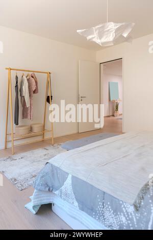 Detail or glimpse of a bedroom interior. One can see the exit and the clothes hanger. The door is open. Stock Photo