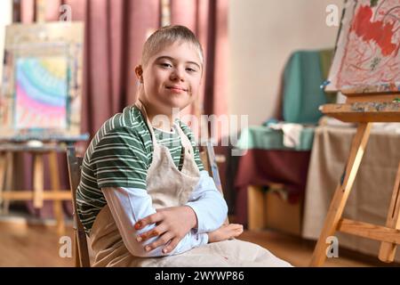 Portrait of smiling teen boy with Down syndrome smiling at camera in art studio copy space Stock Photo