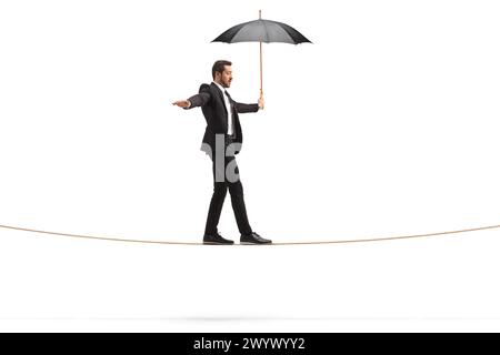 Full length profile shot of a businessman with an umbrella walking on a rope isolated on white background Stock Photo