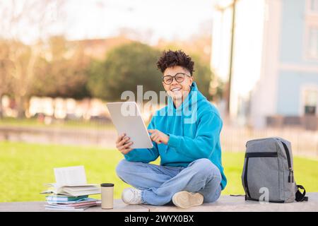 Happy student using tablet outside, studying at park Stock Photo