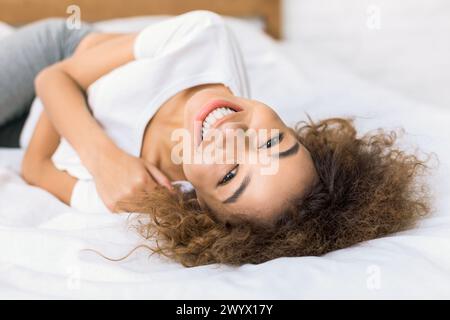 Happy woman lying on bed and looking at camera Stock Photo