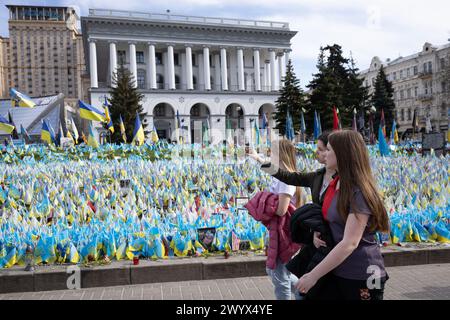 April 5, 2024, Kyiv, Ukraine: Girls walk near an improvised memorial site on Independence Square in Kyiv, where relatives and friends plant Ukrainian flags with the names of military personnel killed in battles with the Russian army. Ukrainian capital is located away from the fighting places, but the presence of war is felt in the city and affects many aspects of the life of local residents. Russian troops entered Ukrainian territory on February 2022, starting a conflict that provoked the destruction of areas and humanitarian crisis. (Credit Image: © Oleksii Chumachenko/SOPA Images via ZUMA Pr Stock Photo