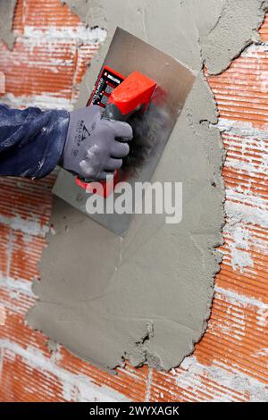 Rendering a brick wall using trowel, new homes under construction, construction site. Stock Photo