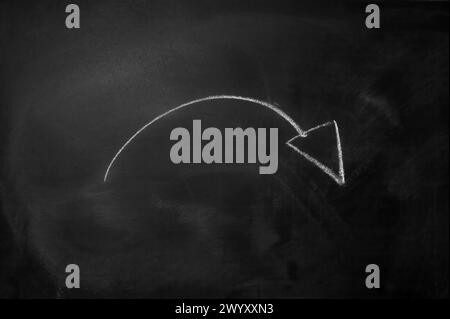 Curved arrow drawn with white chalk on a black blackboard Stock Photo
