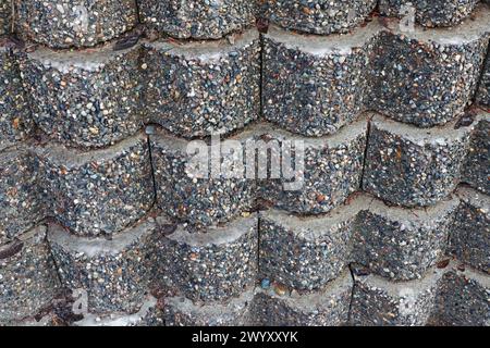 A concrete retaining wall made of various small colored stones Stock Photo