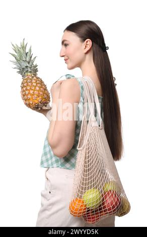 Woman with string bag of fresh fruits holding pineapple on white background Stock Photo