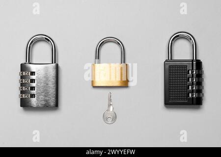Different padlocks and key on grey background, flat lay Stock Photo