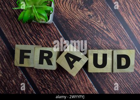 Concept of The wooden Cubes with the word Fraud on wooden background. Stock Photo