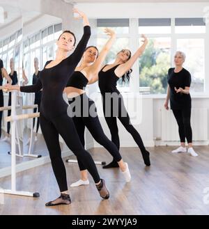 Woman practicing battement tendu at barre in ballet class with instructor Stock Photo