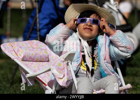 Washington, United States. 08th Apr, 2024. Kendall Chacon of Mexico City use special glasses to look up at the partial solar eclipse from the based of the Washington Monument on the National Mall on April 8, 2024 in Washington, DC (Photo by Samuel Corum/Sipa USA) Credit: Sipa USA/Alamy Live News Stock Photo