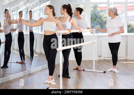 Women practicing ballet moves at barre during group class Stock Photo