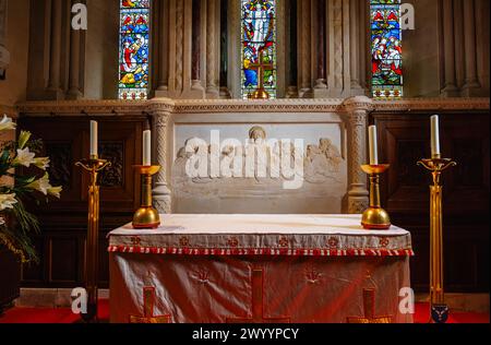 Ashlar reredos behind the altar depicting the ‘Last Supper’ in St Michael & All Angels parish church in Mickleham, a village near Dorking, Surrey Stock Photo