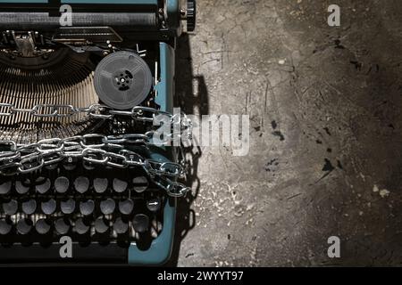 Vintage typewriter with chains on grey grunge background. Printing ban concept Stock Photo