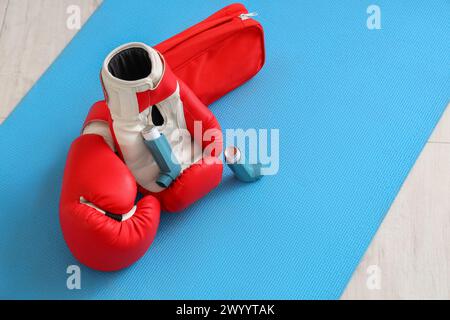 Asthma inhalers with boxing gloves and first aid kit on mat in gym ...