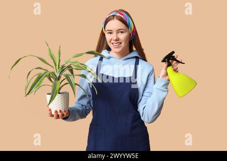 Pretty young woman with houseplant and water sprayer on beige background Stock Photo