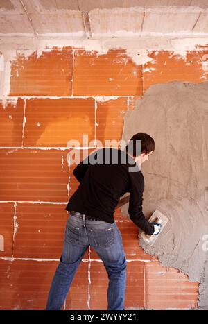 Bricklayer, rendering a partition wall, new homes under construction, construction site. Stock Photo