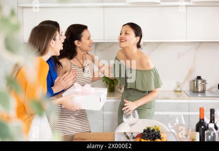 Three women have arrived for birthday celebration and presenting gift to birthday woman Stock Photo