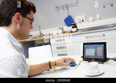 Person using a personal medicine assistant The person brings the medicine closer to the reader in order to know if that medicine should be taken in the next dose, Home lab for testing and research trials for patients at home, Unit of Health Technology, Tecnalia Research & Innovation, Bizkaia Technology Park, Zamudio, Basque Country, Spain. Stock Photo