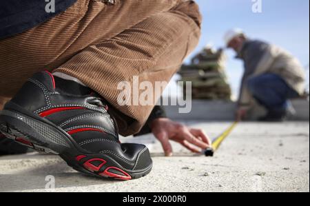 Construction workers measuring, personal protective equipment, housing construction. Stock Photo