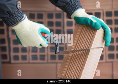 Cutting brick mason with trowel, housing construction. Stock Photo