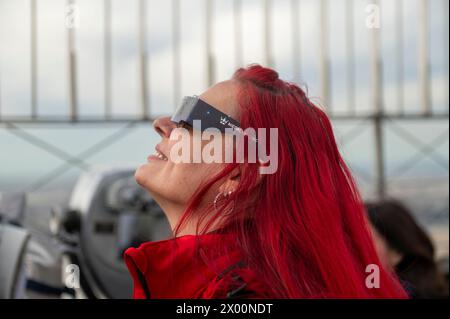 New York, New York, USA. 8th Apr, 2024. (NEW) Solar Eclipse 2024 in New York City. April 08, 2024, New York, New York, USA: A woman wearing protective glasses views the partial solar eclipse from the 86th floor Observation deck of the Empire State Building on April 8, 2024 in New York City. With the first solar eclipse to pass through North America in seven years, New York City was not in the path of totality, with only 90% of the sun covered by the moon; the next eclipse visible in the United States will be in 2044. (Credit: M10s/TheNews2) (Foto: M10s/Thenews2/Zumapress) (Credit I Stock Photo