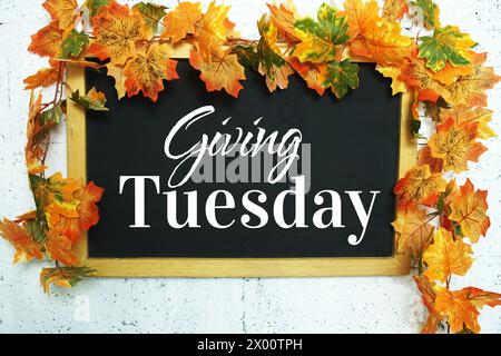 Giving Tuesday text message on chalkboard with maple leaf decoration Stock Photo