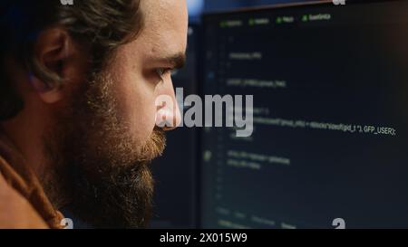 Software engineer concerned, concentrating on finding bugs while coding on computer, extreme close up. Troubled IT professional frowning while looking at screen, confused by script errors, camera A Stock Photo