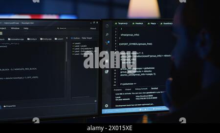Software engineer writes complex binary code scripts on computer, close up. Teleworking IT specialist in home office using programming to safeguard consumer data, handheld camera shot, camera A Stock Photo